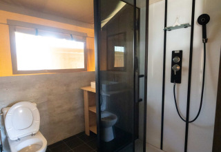 Bathroom in a safari tent lodge at Eurocamping Vessem BV in the Netherlands, with shower and toilet.