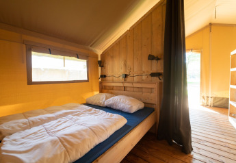 Safari tent with sanitary facilities at Eurocamping Vessem BV, Netherlands, bright and cozy bedroom.