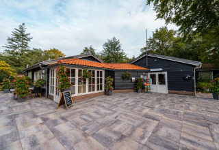 Foto di un villaggio vacanze con case in legno scuro, reception e fiori, ideale per soggiorni glamping.