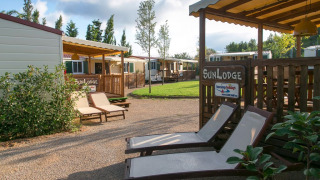 Zonnige chalets met ligstoelen en groen grasveld in het SunLodge-gedeelte, ideaal om buiten te relaxen.