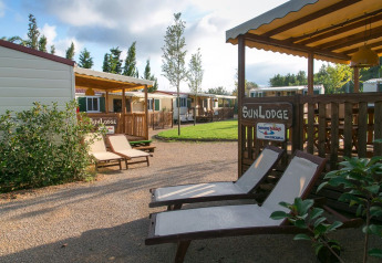 Zonnige chalets met ligstoelen en groen grasveld in het SunLodge-gedeelte, ideaal om buiten te relaxen.