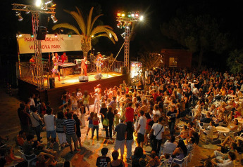 Concert et danse en soirée sur un site de glamping avec scène, groupe et public animé.