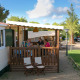 Family enjoys an outdoor meal on the veranda of a SunLodge Redwood cabin surrounded by greenery.