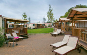SunLodge Redwood chalets met ligstoelen en gazon op Camping Vilanova Park in Spanje.