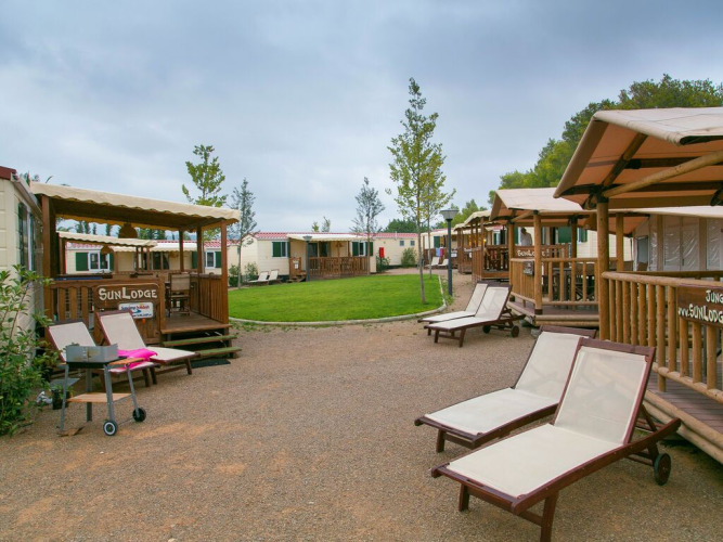 SunLodge Redwood cabins with loungers and green lawn area at Camping Vilanova Park in Spain.
