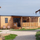 Billede af SunLodge Catalpa, en moderne træhytte med veranda, stole og grønne omgivelser på lodgen.