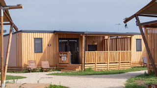 Photo du SunLodge Catalpa, un pavillon moderne en bois avec terrasse, chaises et sentier de graviers.