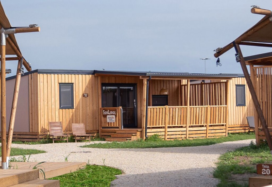 Billede af SunLodge Catalpa, en moderne træhytte med veranda, stole og grønne omgivelser på lodgen.