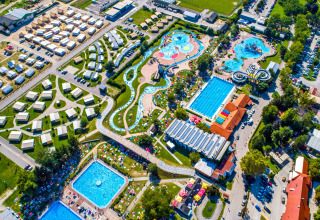 Vista aérea de un alojamiento glamping con tiendas de lujo, piscinas, toboganes de agua y áreas verdes.