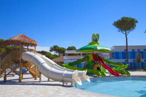 Kindvriendelijk waterpark met glijbanen en vrolijke decoratie bij een lodge onder een blauwe hemel.