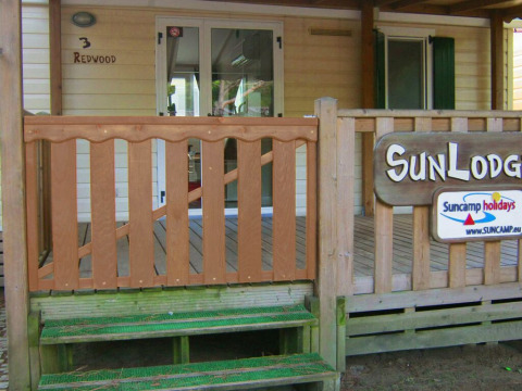 Entrada de SunLodge Redwood en hu Park Albatros Village en Italia, con porche y señales visibles.