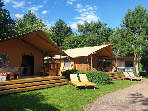 Billede af SunLodge Yucca safaritelt på hu Birkelt Village i Luxembourg, omgivet af grønne træer og liggestole.