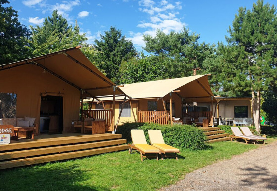 Billede af SunLodge Yucca safaritelt på hu Birkelt Village i Luxembourg, omgivet af grønne træer og liggestole.