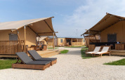 Sunny tent lodges and lounge chairs at SunLodge Taiga, Camping Cisano/San Vito, Italy, exterior view.