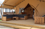 Covered wooden patio with outdoor lounge seating at the SunLodge Taiga, Camping Cisano/San Vito in Italy.