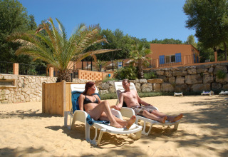 Pareja relajándose en tumbonas frente a una tienda safari en Slow Village Provence Occitane, Francia.