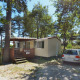 Solrig dag ved SunLodge Redwood, Camping Village Mare Pineta, Italien. Mobilhome og bil i skovområde.