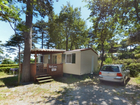 Día soleado en SunLodge Redwood, Camping Village Mare Pineta, Italia. Casa móvil y coche en el bosque.