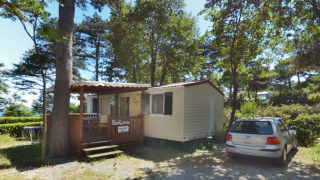 Día soleado en SunLodge Redwood, Camping Village Mare Pineta, Italia. Casa móvil y coche en el bosque.