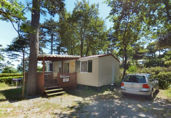 Día soleado en SunLodge Redwood, Camping Village Mare Pineta, Italia. Casa móvil y coche en el bosque.