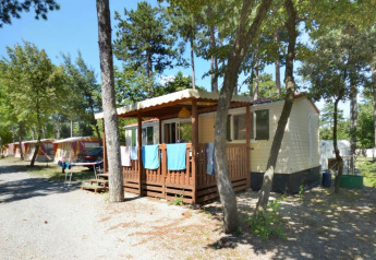 SunLodge Redwood lodge op Camping Village Mare Pineta in Italië, omringd door bomen en natuur.