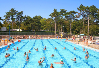 Piscina all'aperto presso un lodge con molte persone che nuotano e si rilassano in una giornata soleggiata.