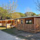 Houten chalets bij SunLodge Sabai op Camping Union Lido Mare in Italië, omgeven door bomen en natuur.