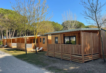 Wooden lodges at SunLodge Sabai, Camping Union Lido Mare in Italy, surrounded by trees and nature.
