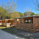 Cabañas de madera en SunLodge Sabai, Camping Union Lido Mare en Italia, rodeadas de árboles y naturaleza.