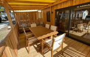 Buitenruimte met houten tafel en stoelen onder gele luifel bij SunLodge Sabai, Union Lido Mare, Italië.
