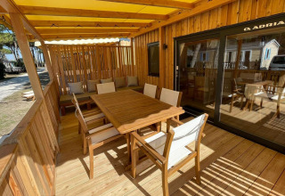 Terraza exterior con muebles de madera y toldo amarillo en SunLodge Sabai, Camping Union Lido Mare, Italia.