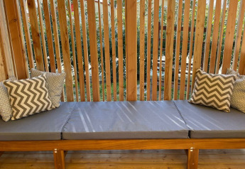 Banc extérieur avec coussins gris et oreillers à motifs à SunLodge Sabai, Camping Union Lido Mare, Italie.