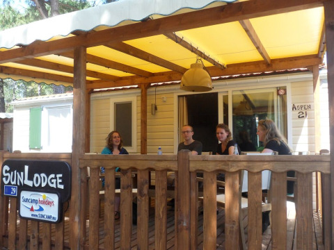 Quattro persone sedute sulla veranda di una SunLodge Aspen al Camping Village Cavallino, Italia.