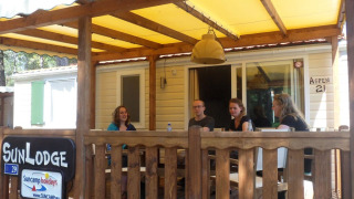 Quattro persone sedute sulla veranda di una SunLodge Aspen al Camping Village Cavallino, Italia.