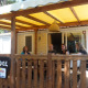 Fire personer sidder på en overdækket terrasse ved SunLodge Aspen på Camping Village Cavallino i Italien.