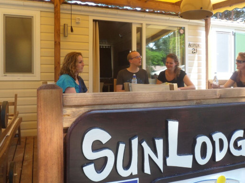 Vier personen zitten aan een buitentafel bij SunLodge Aspen op Camping Village Cavallino, Italië.