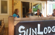 Vier personen zitten aan een buitentafel bij SunLodge Aspen op Camping Village Cavallino, Italië.