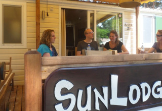 Quatre personnes assises à une table extérieure à SunLodge Aspen au Camping Village Cavallino, Italie.