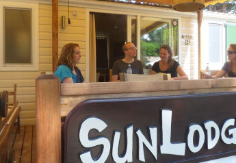 Quatre personnes assises à une table extérieure à SunLodge Aspen au Camping Village Cavallino, Italie.