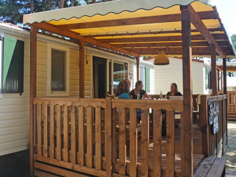 Terrasse en bois à SunLodge Aspen, Camping Village Cavallino, Italie, avec des personnes discutant.