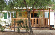 SunLodge Aspen con porche de madera en Camping Leï Suves, Francia, rodeada de vegetación y tranquilidad.