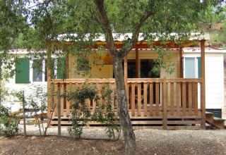 SunLodge Aspen bij Camping Leï Suves in Frankrijk, houten veranda omringd door bomen en natuur.
