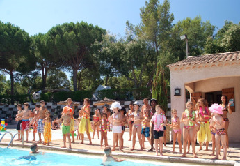 Bambini e adulti in costume si divertono vicino alla piscina in una sistemazione glamping immersa nel verde.