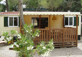 SunLodge Redwood au Camping Leï Suves en France, avec véranda en bois et arbustes fleuris devant.