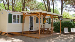 Buitenaanzicht van SunLodge Maple aan Camping Village Marina di Venezia met een overdekt terras en stoelen.