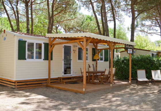 Buitenaanzicht van SunLodge Maple aan Camping Village Marina di Venezia met een overdekt terras en stoelen.