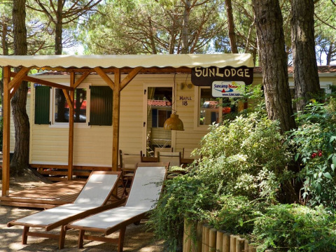 Zonnige SunLodge Maple lodge op Camping Village Marina di Venezia, Italië, met ligstoelen vooraan.