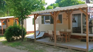 Bungalow SunLodge Aspen Combi al Camping Union Lido Mare in Italia, con veranda e tavolo all'aperto.