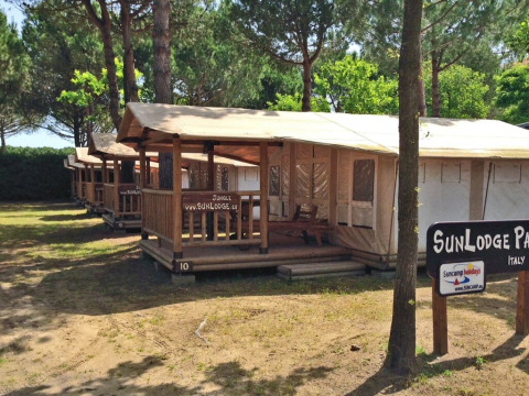 Række af SunLodge Jungle telte på Camping Union Lido Mare i Italien, omgivet af træer og skygge.