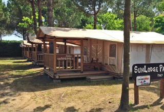 Row of SunLodge Jungle tents at Camping Union Lido Mare in Italy, surrounded by trees and shade.